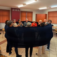 seniorzy w kręgu, owinięci czrnym materiałem